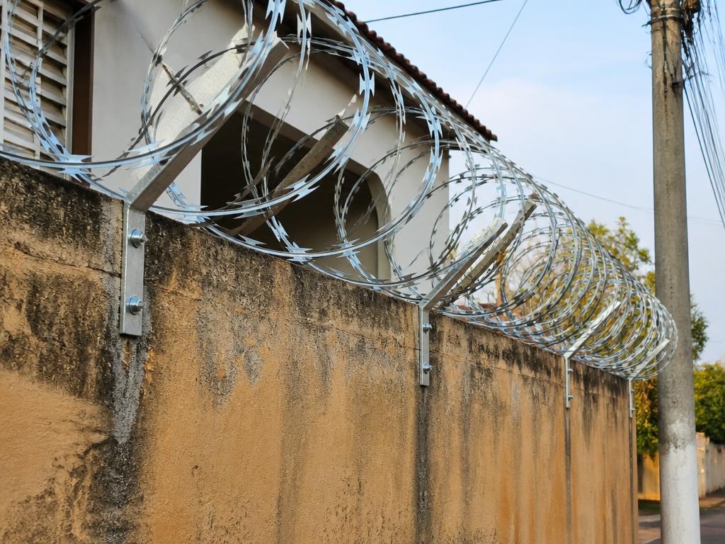 Concertina de aço galvanizado instalada sobre muro de concreto
